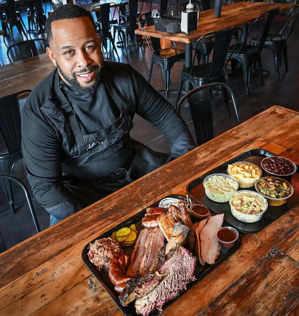 Fresno native and Horn Barbecue founder Matt Horn sits with a selection of barbecue meats and sides at his new restaurant at its opening in Fresno's Granite Park shopping center on Jan. 20, 2026.