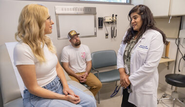 Female patient and husband listen to doctor in exam room