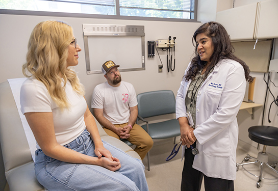 Female patient and husband listen to doctor in exam room