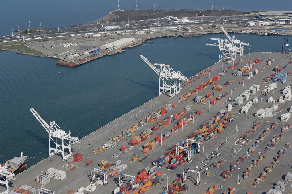 Aerial view of the Port of Oakland with shipping containers, cranes, and ships.