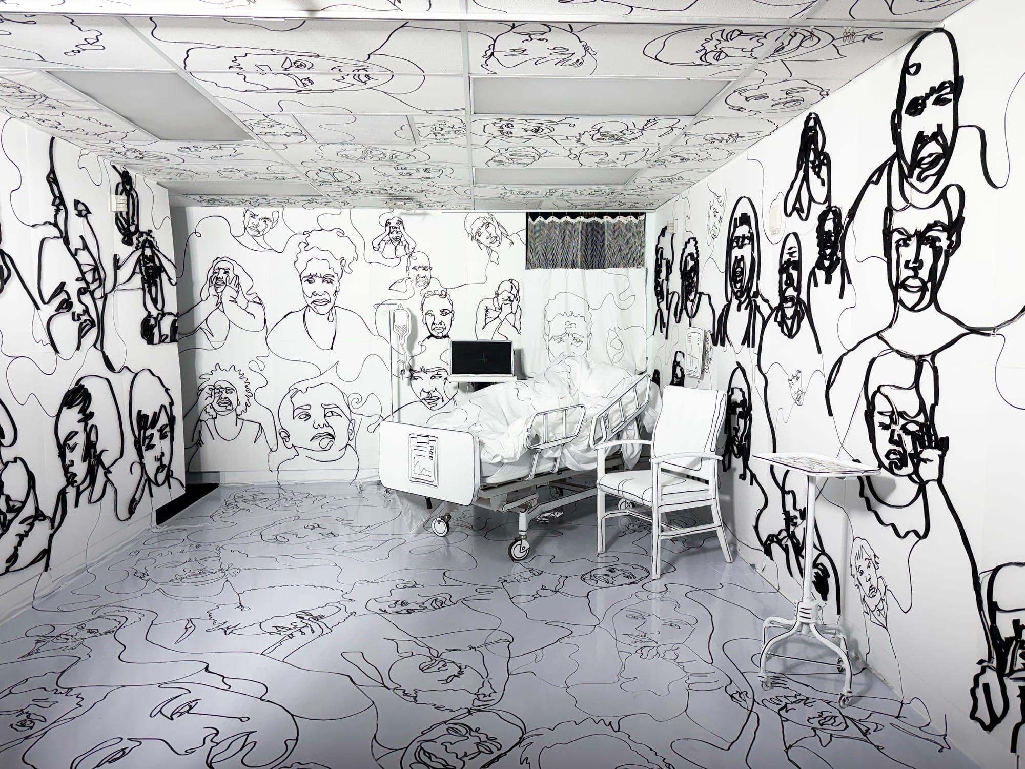 a hospital room installation transformed by black figurative line drawings on every surface