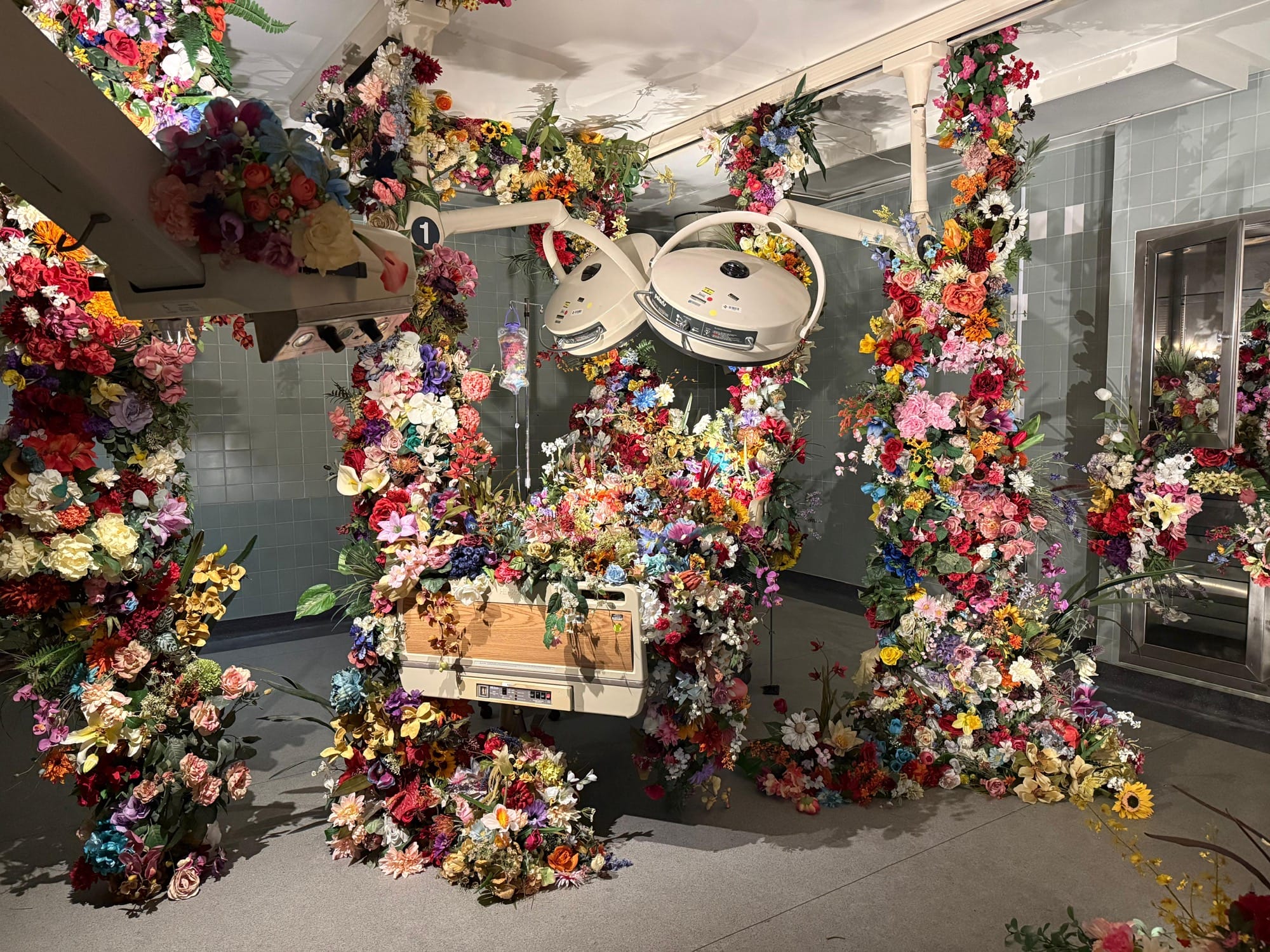 a hospital room installation transformed by lush installations of flowers