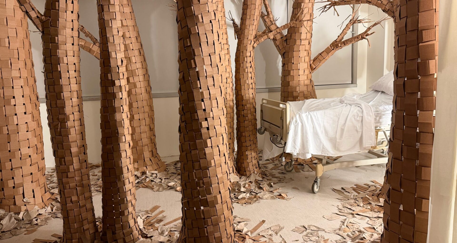 a hospital room installation transformed by large paper trees