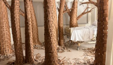 a hospital room installation transformed by large paper trees