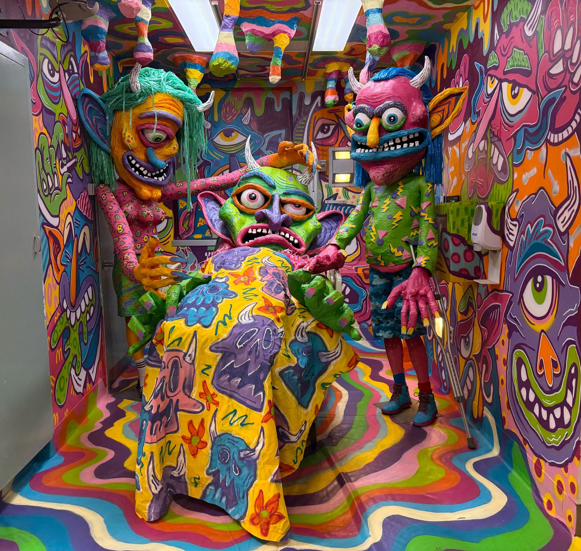 a hospital room installation transformed by monster-like characters and vibrant paint