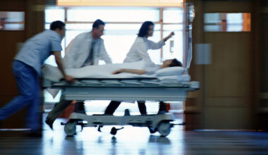 a motion-blurred image of medical workers pushing a patient on a gurney down a hospital corridor