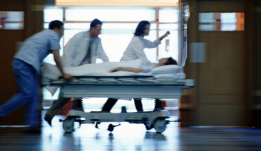 a motion-blurred image of medical workers pushing a patient on a gurney down a hospital corridor