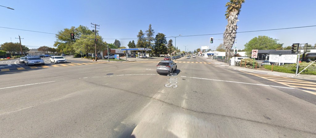 A wide shot of Soto Road with a gas station, a brake repair shop, and cars at a busy intersection.