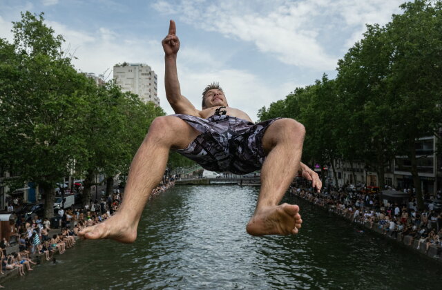 TOPSHOT - A swimmer dives into the Canal Saint-Martin, from an unapproved spot for swimming as France experiences a heatwave in Paris on June 20, 2026. Due to the ongoing heatwave sweeping across France - the Bassin des Recollets - a portion of the Canal Saint-Martin in the French capital has been opened for swimming from June 17. France issued a red heatwave alert across more than a third of the country for June 21, as a ferocious heatwave dug in and the government banned the consumption of alcohol in certain areas during the annual Fete de la Musique festivities. (Photo by ARNAUD FINISTRE / AFP via Getty Images)