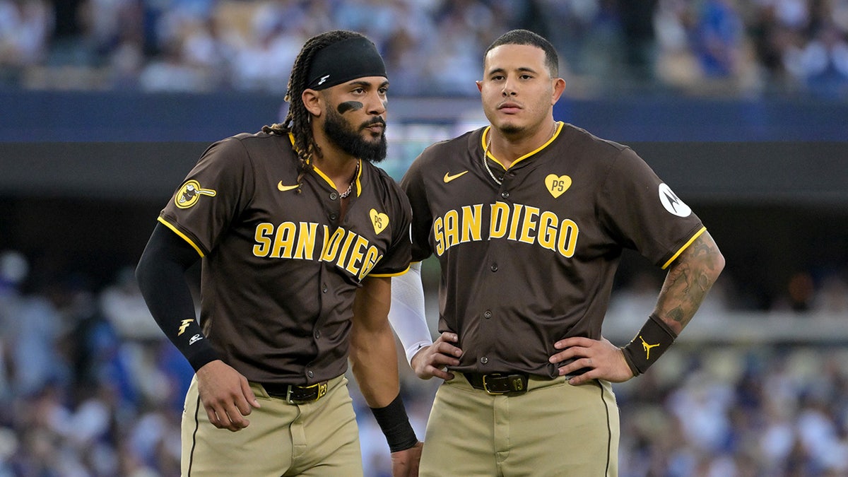 San Diego Padres outfield Fernando Tatis Jr. and third baseman Manny Machado looking on during a baseball game.