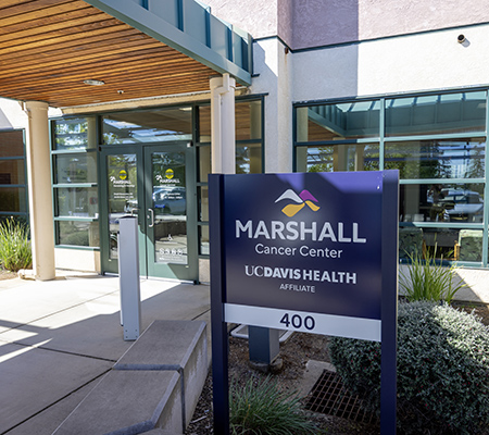 Exterior of building with glass doors and sign in the foreground that reads, “Marshall Cancer Center, UC Davis Health affiliate”
