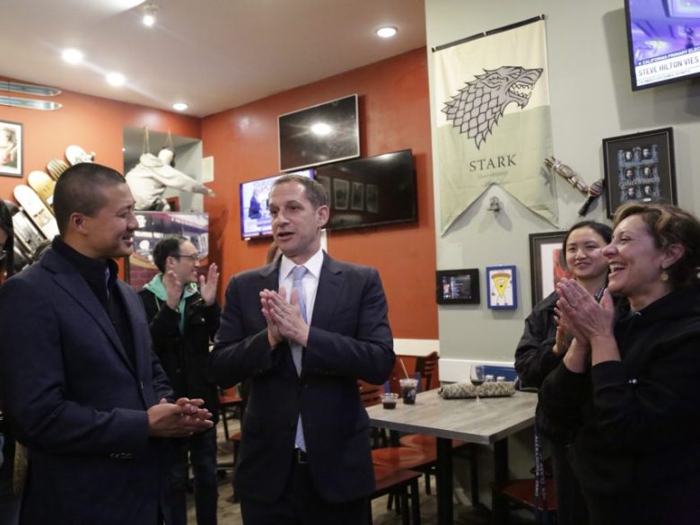 A group of people stand and converse in a restaurant decorated with a Stark banner from Game of Thrones and skateboard decks on the wall.