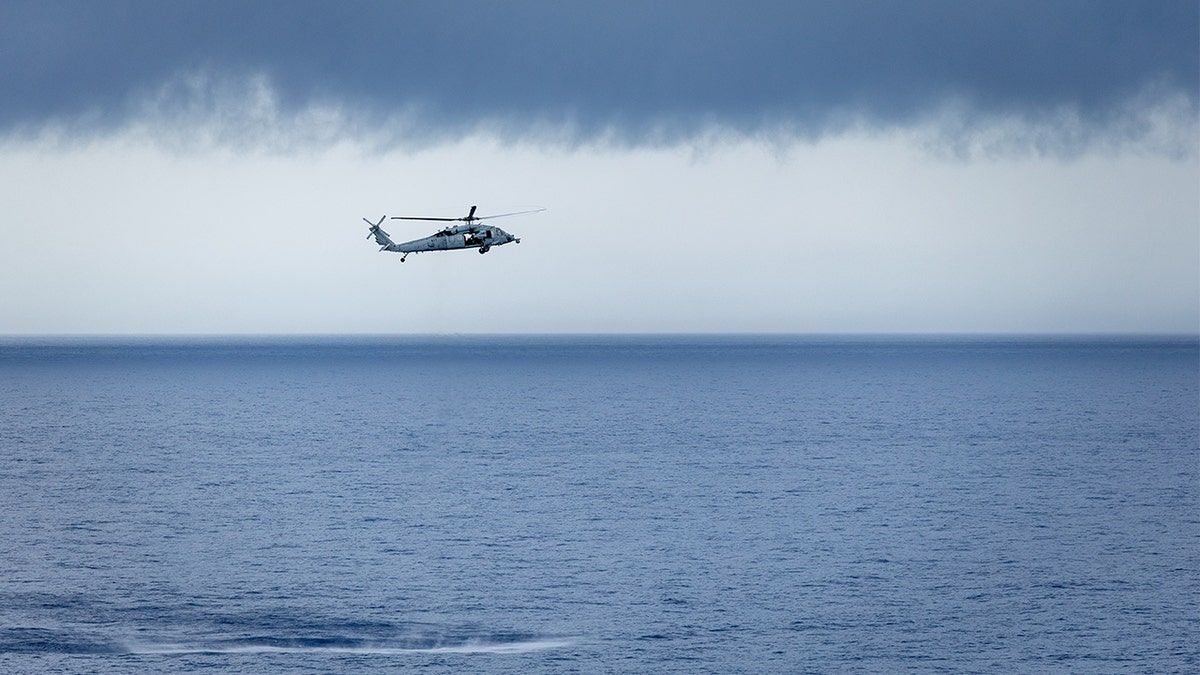 US Navy helicopter flies above ocean