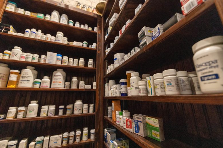 Shelves stocked with various pharmaceutical bottles and boxes in a pharmacy.