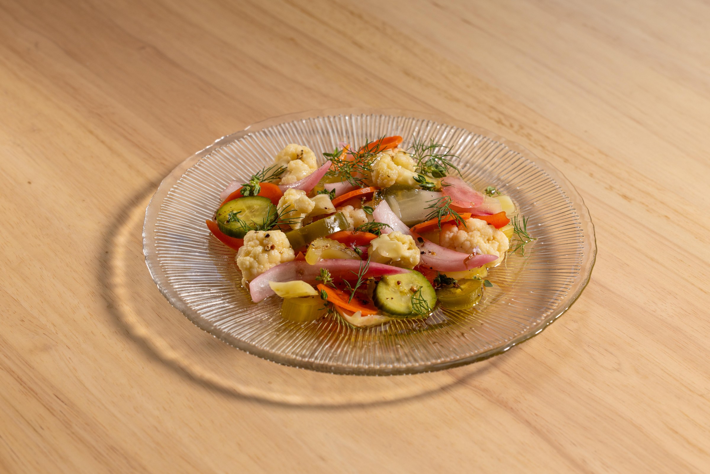 Giardiniera on a clear plate sitting on a light wood table at Pizzeria Sei.