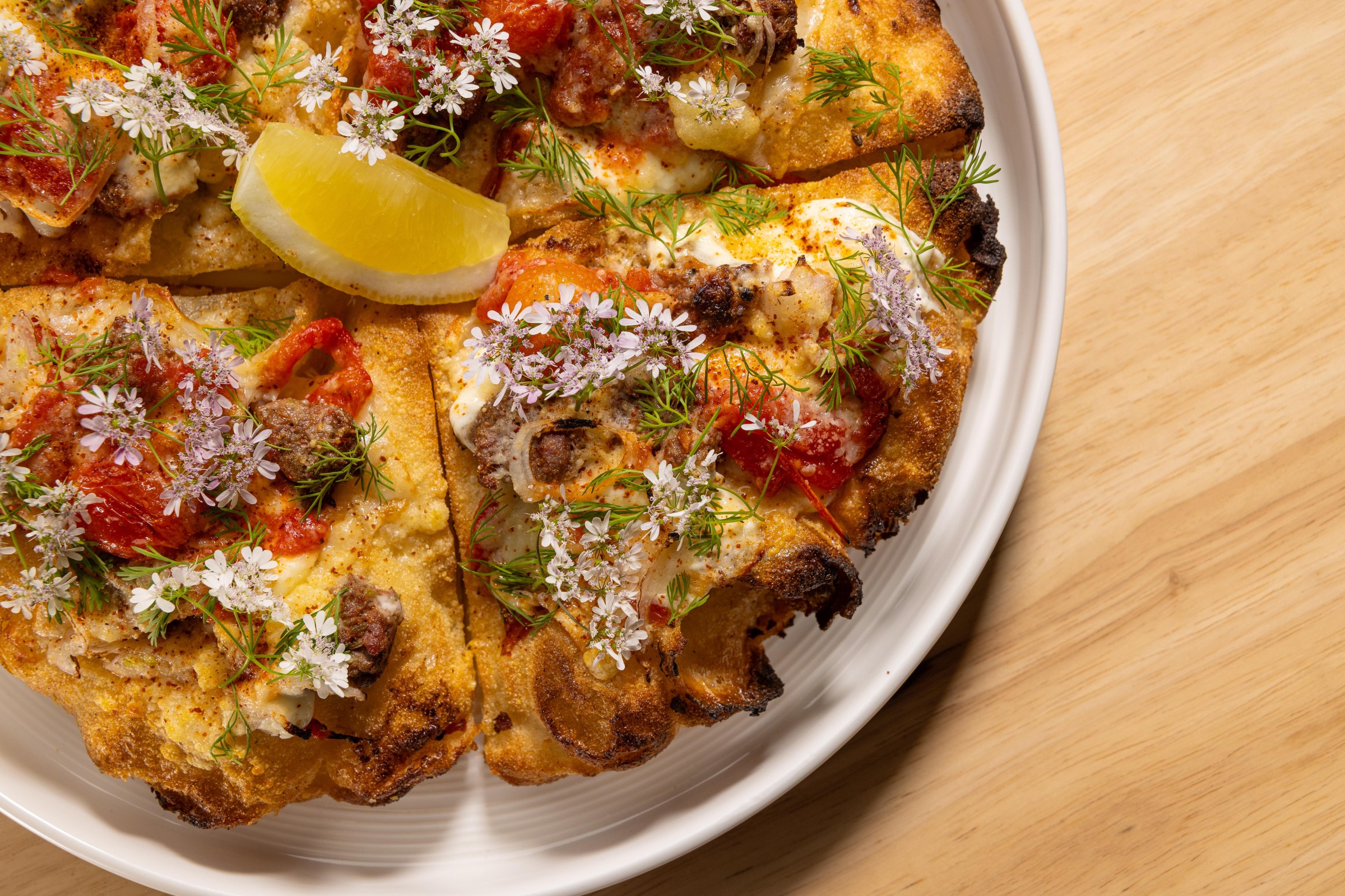 Overhead close-up of pizza montanara at Pizzeria Sei with flower topping and lemon.