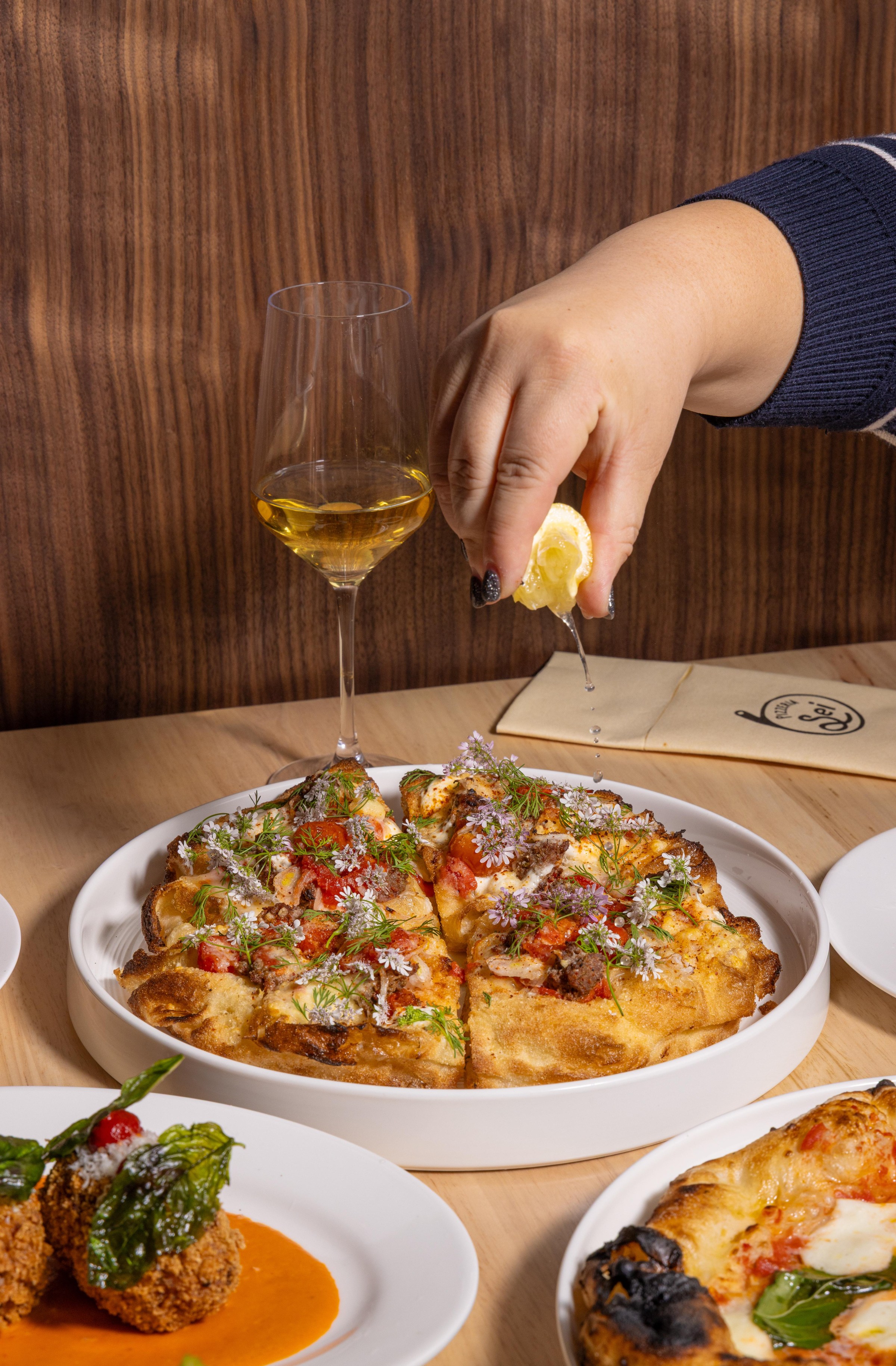 Hand squeezing lemon over pizza montanara at Pizzeria Sei.
