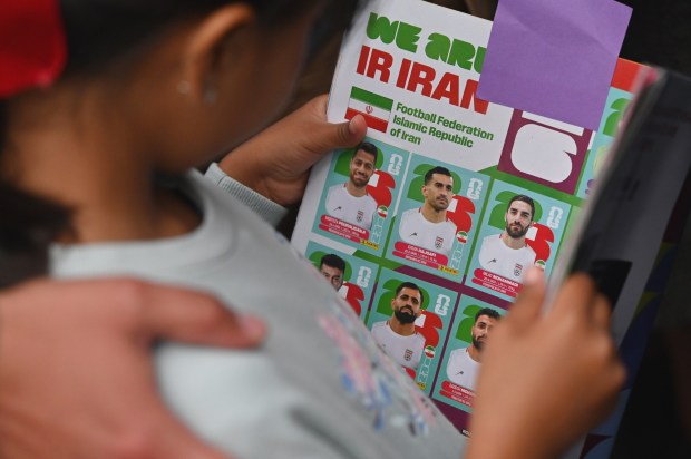 A young fan carries a FIFA World Cup sticker booklet of Iran's national team players as she and others wait for the team to leave the Marriott Hotel at their Tijuana base camp to the airport ahead of the team's departure following its elimination from the 2026 World Cup football tournament in Tijuana, Mexico on Tuesday, June 30, 2026. (Carlos Moreno / The San Diego Union-Tribune)