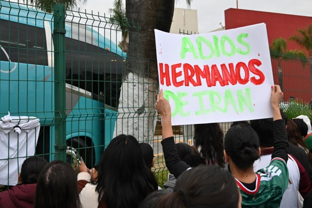A fan carries a sign that reads 'Adios Hermanos De Iran' "Goodbye Iranian Brothers" as they wait for Iran's national team players to leave the Marriott Hotel at their Tijuana base camp to the airport ahead of the team's departure following its elimination from the 2026 World Cup football tournament in Tijuana, Mexico on Tuesday, June 30, 2026. (Carlos Moreno / The San Diego Union-Tribune)