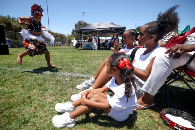 People watch as Zion Alexander, 9, performs with the West African Dance group during the Cooper Family Foundation's annual Juneteenth celebration at Memorial Community Park in Logan Heights in San Diego on Saturday, June 20, 2026. (Hayne Palmour IV / For The San Diego Union-Tribune)