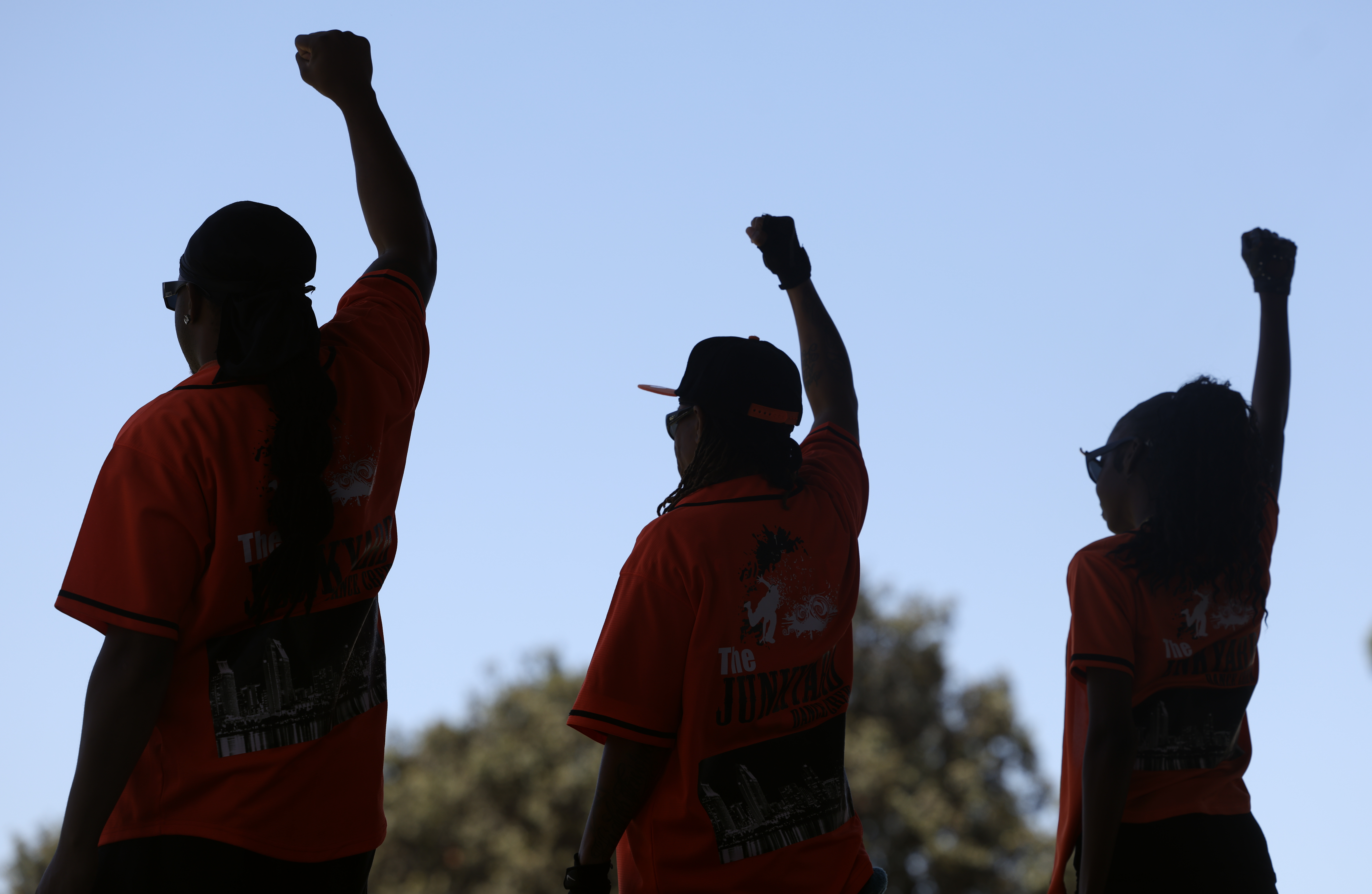 Members of the Junkyard Dance Crew raise their fists at...