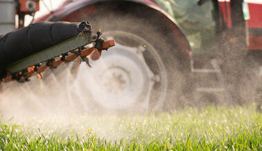 Tractor spraying pesticides over a green field