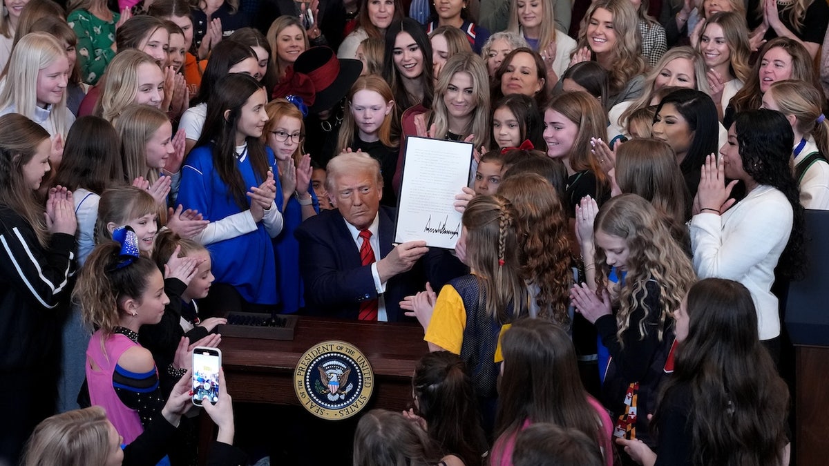 President Donald Trump signing executive order in East Room at White House with women athletes