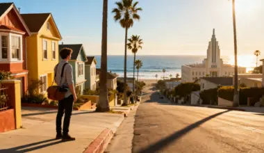 Person with camera bag standing on residential street overlooking ocean at sunset
