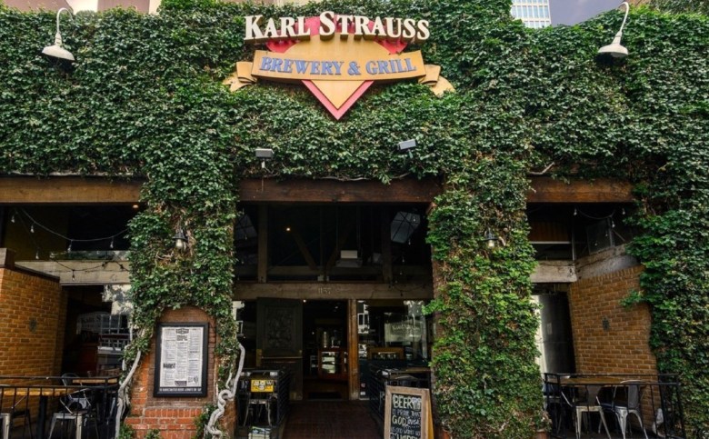 A building with a brick and ivy exterior with a menu hanging on one column and a folding sign showing daily specials.