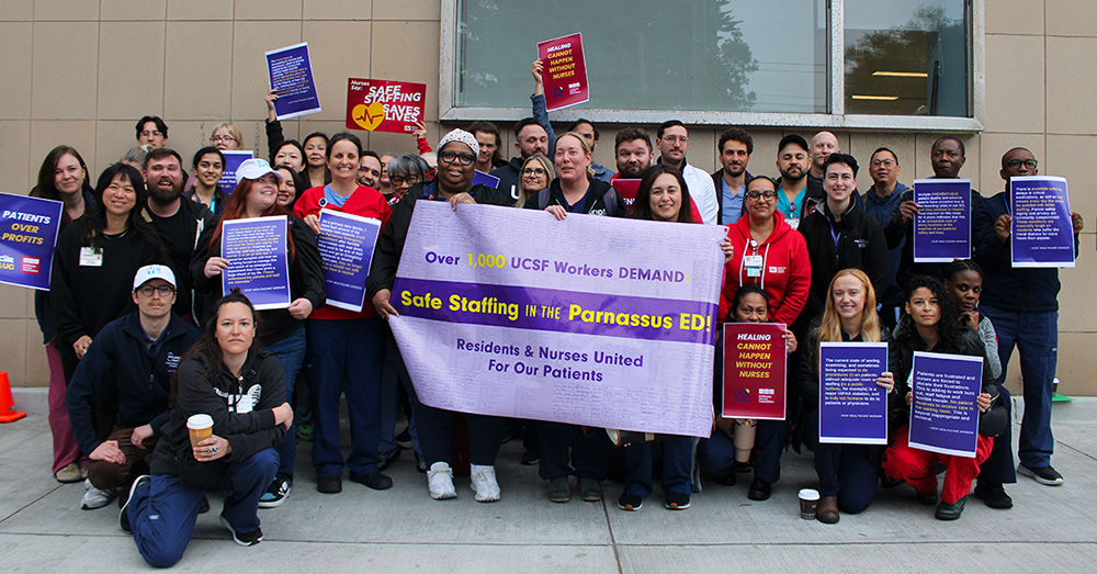 Group of nurses and physicians outside hospital holding banner "UCSF Workers Demand Safe Staffing"