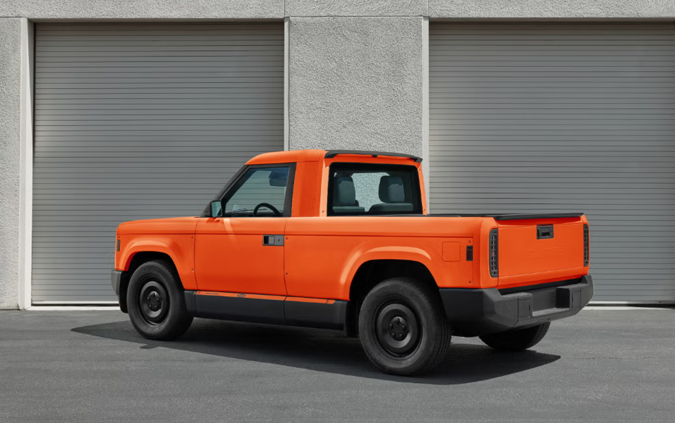 Bright orange pickup truck parked in front of two closed garage doors.