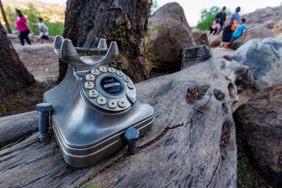 Hikers pass a wind phone that has been vandalized.