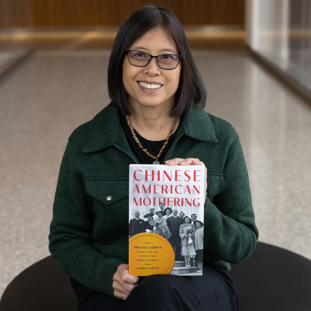 Dr. Andrea Louie smiles holding her book