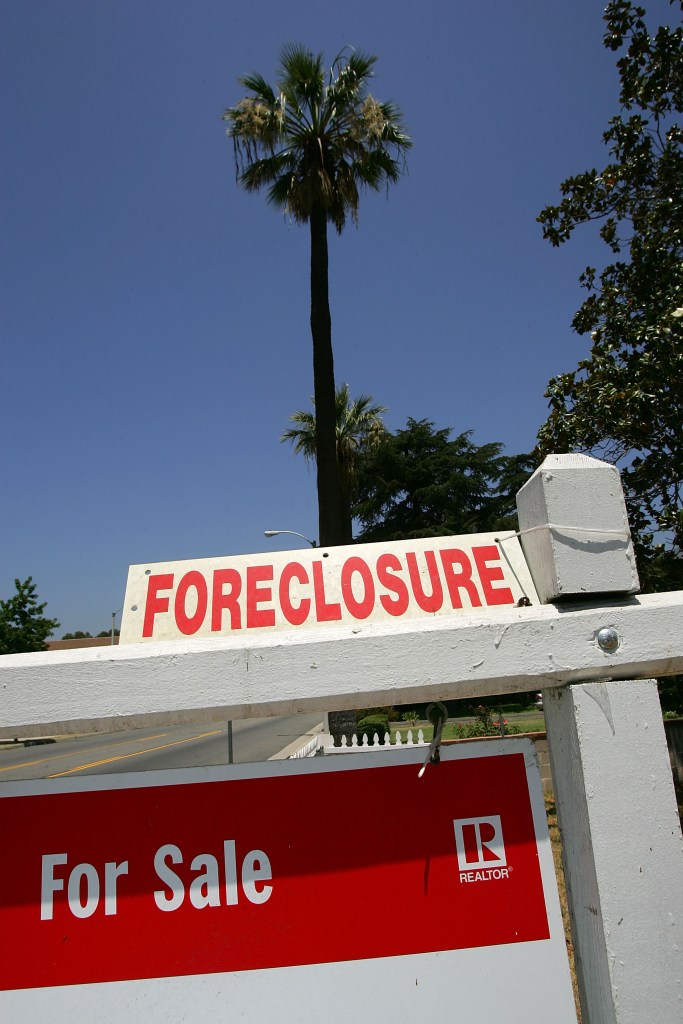 "For Sale" and "Foreclosure" signs in front of a house.