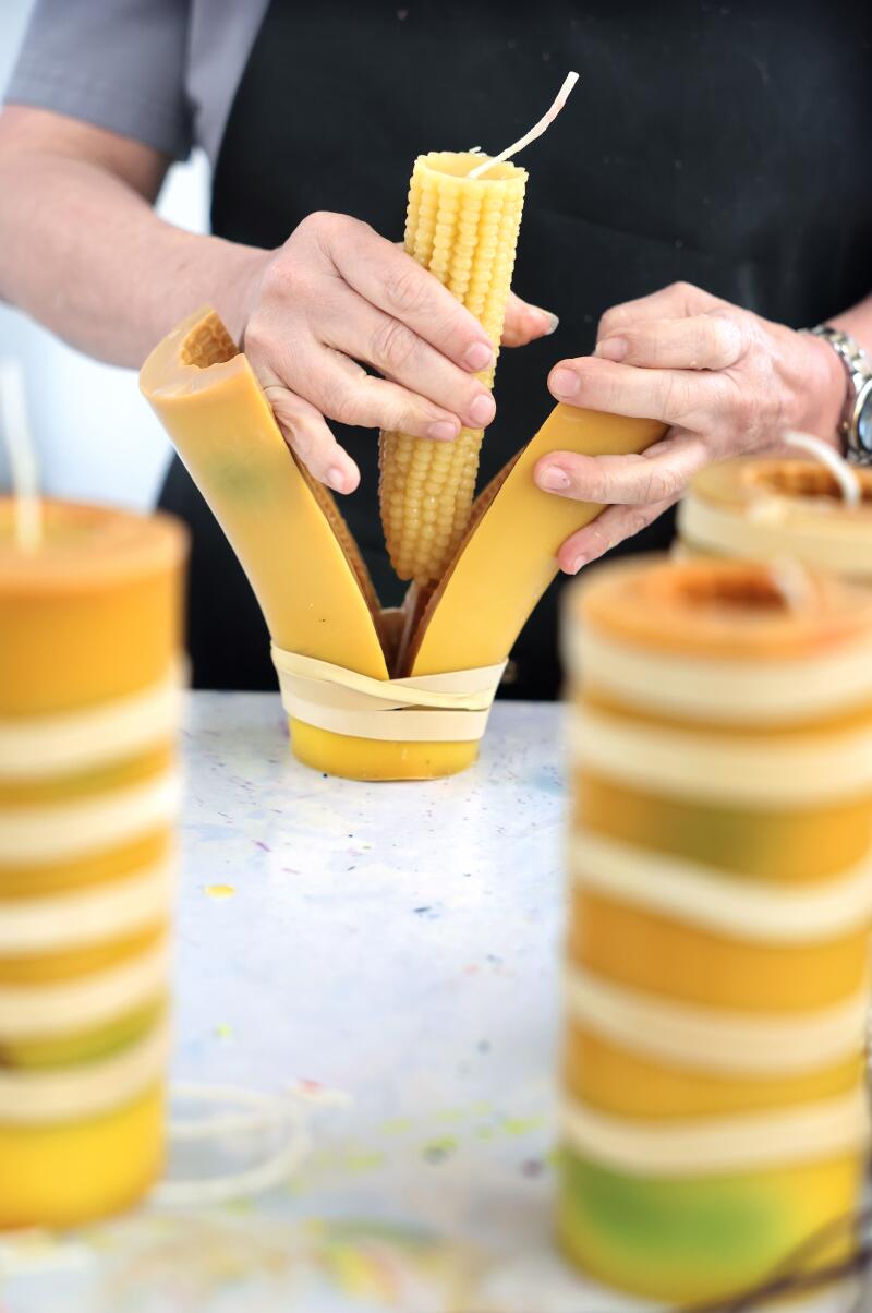 A worker pulls a corn candle out of its mold.