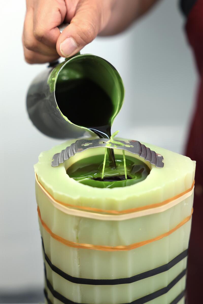 A worker pours wax into a mold for a cactus candle