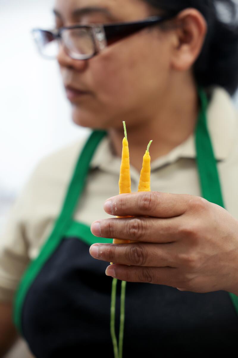 A staff member trims the wicks on a pair of carrot birthday candles, $22.
