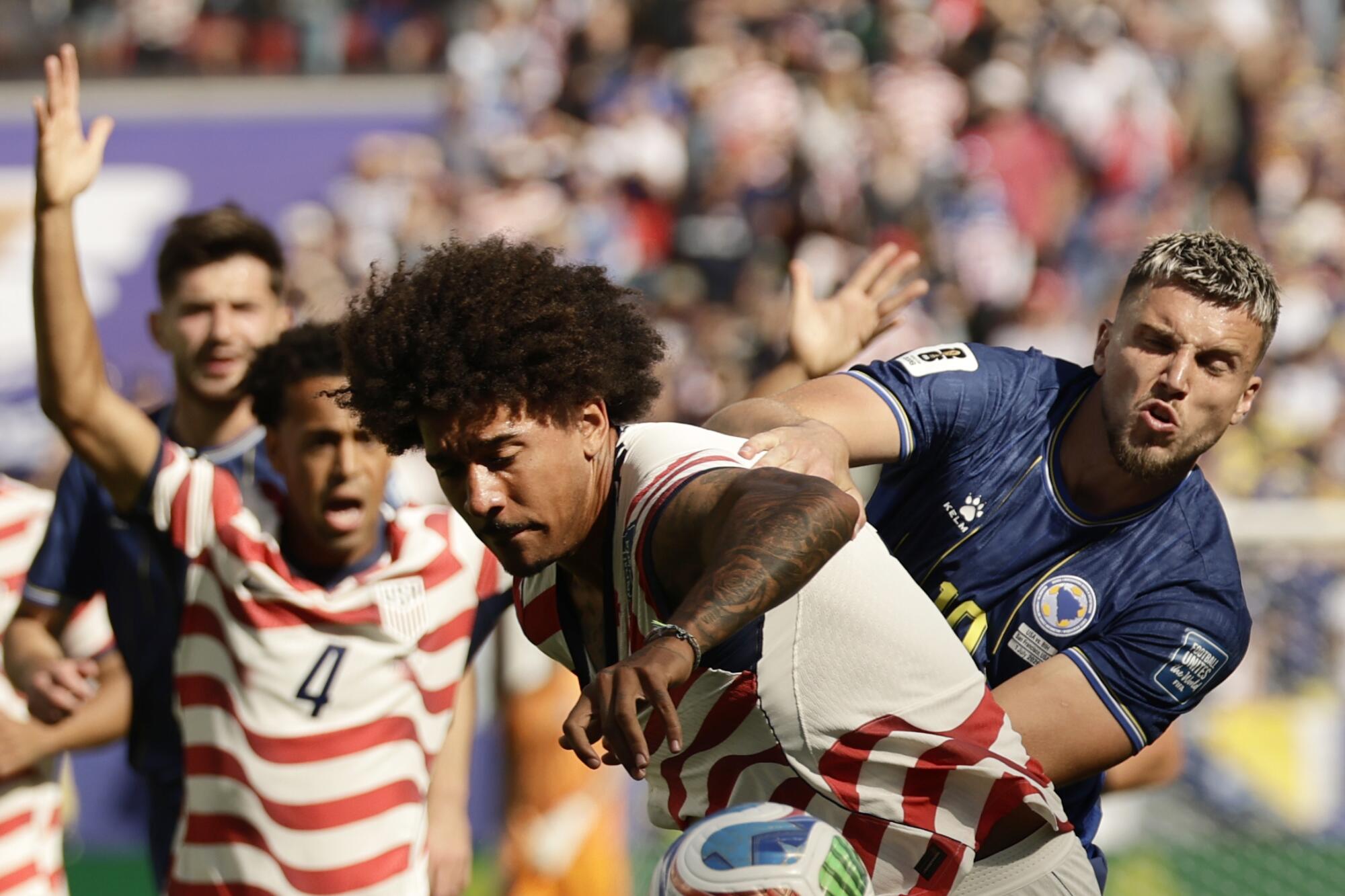 Bosnia-Herzegovina forward Ermedin Demirovic grabs U.S. defender Chris Richards during a World Cup match.