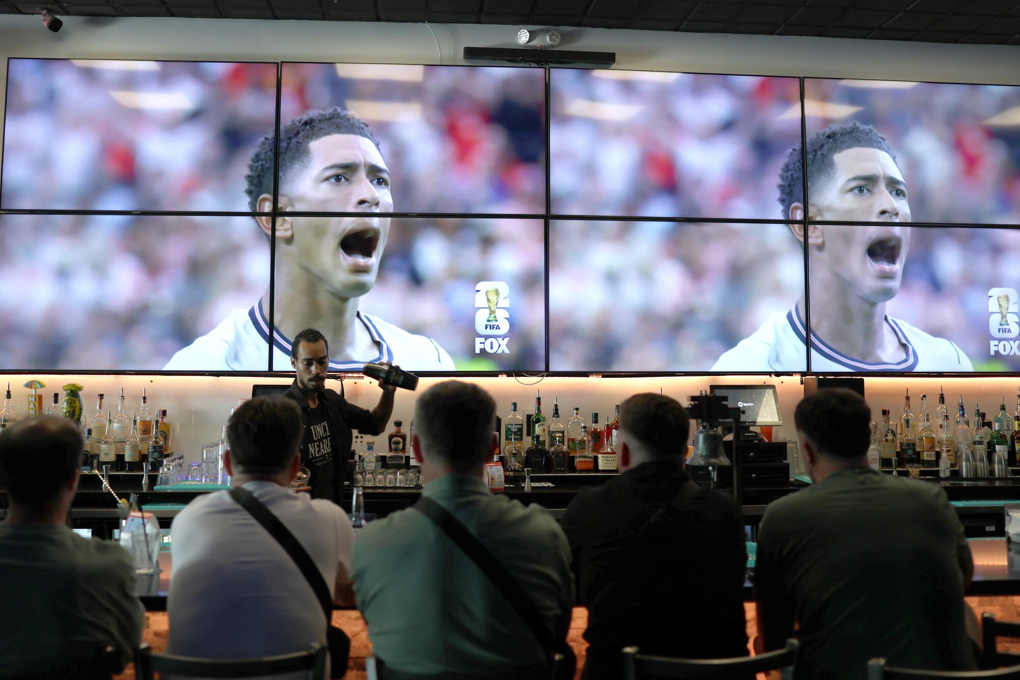 Bartender Elijah Gonzalez mixes a drink at the Nile Bar while customers watch Croatia play England