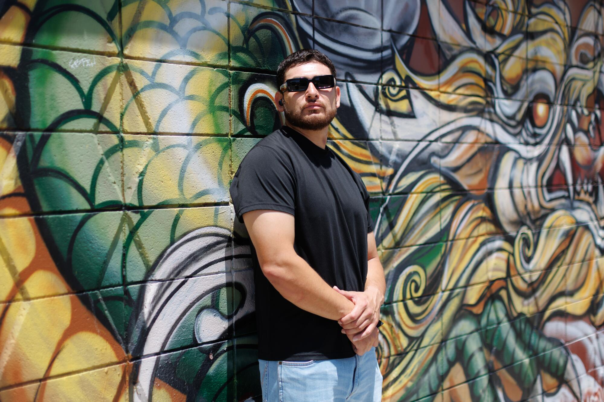 A person leaning against an outdoor mural.