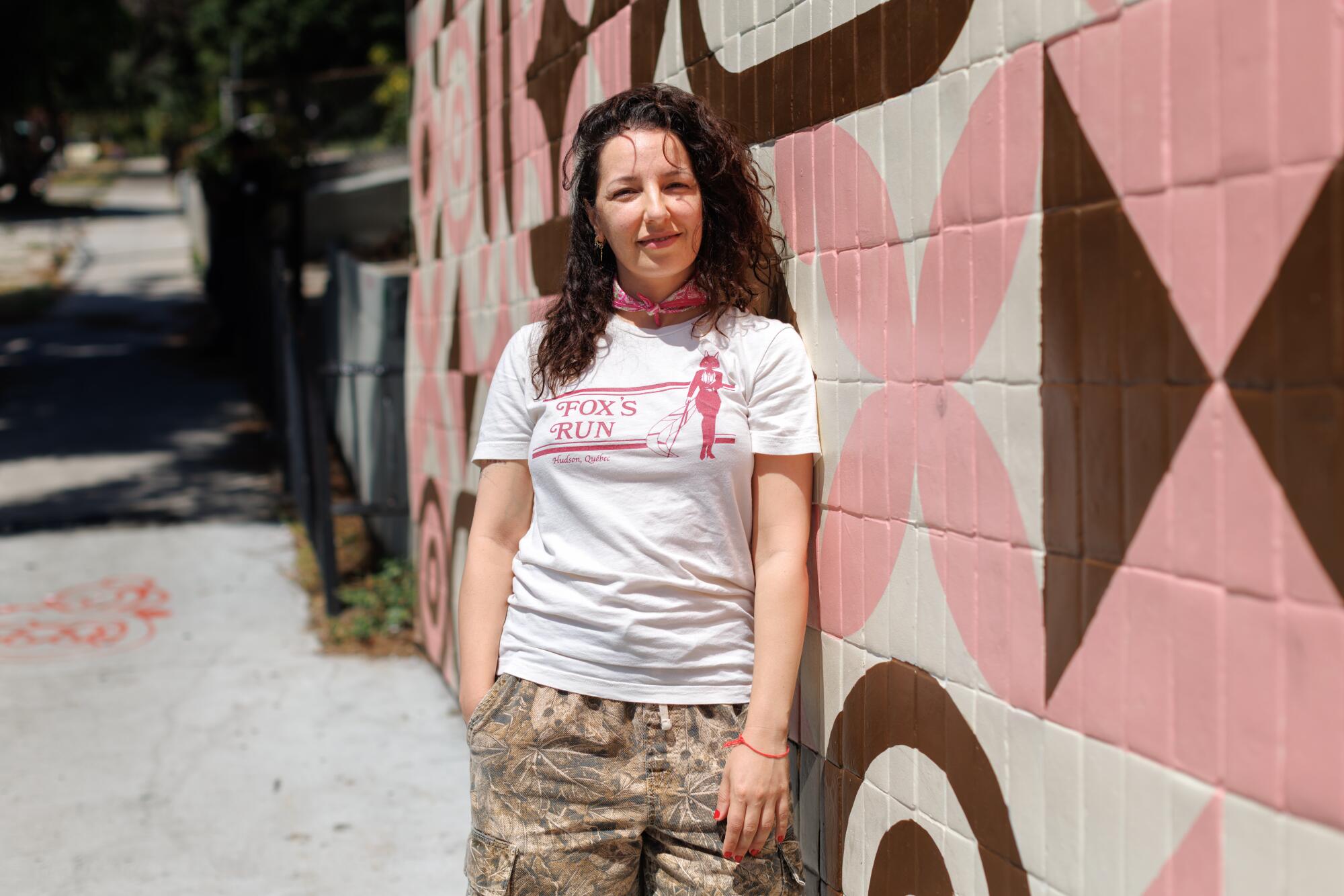 A person standing outside by a mural.
