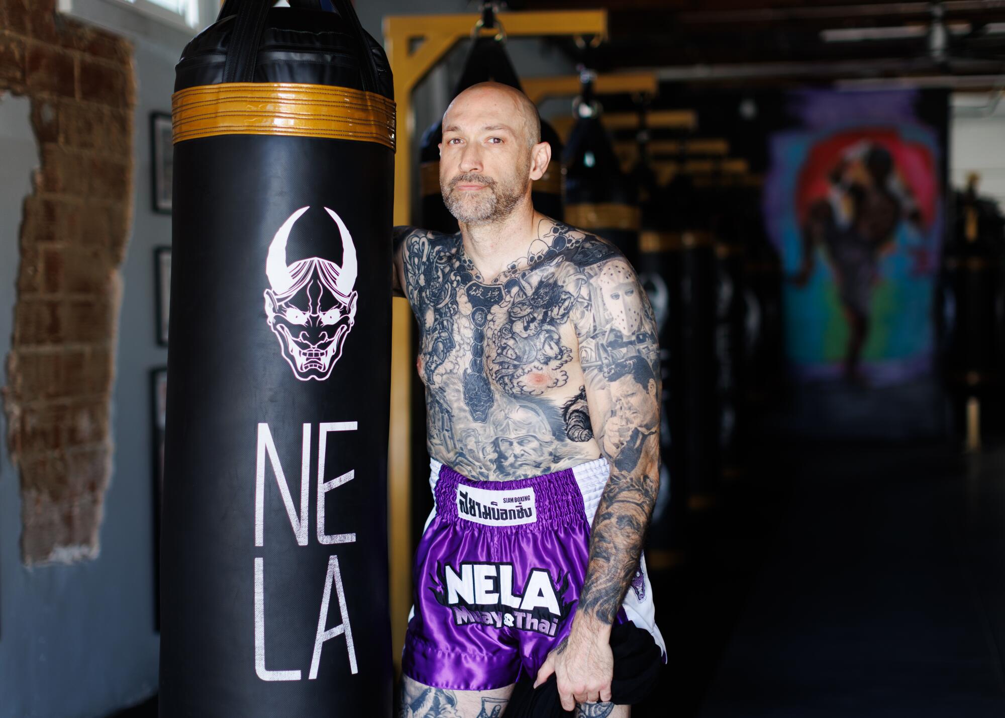 A person standing inside a gym with a punching bag.