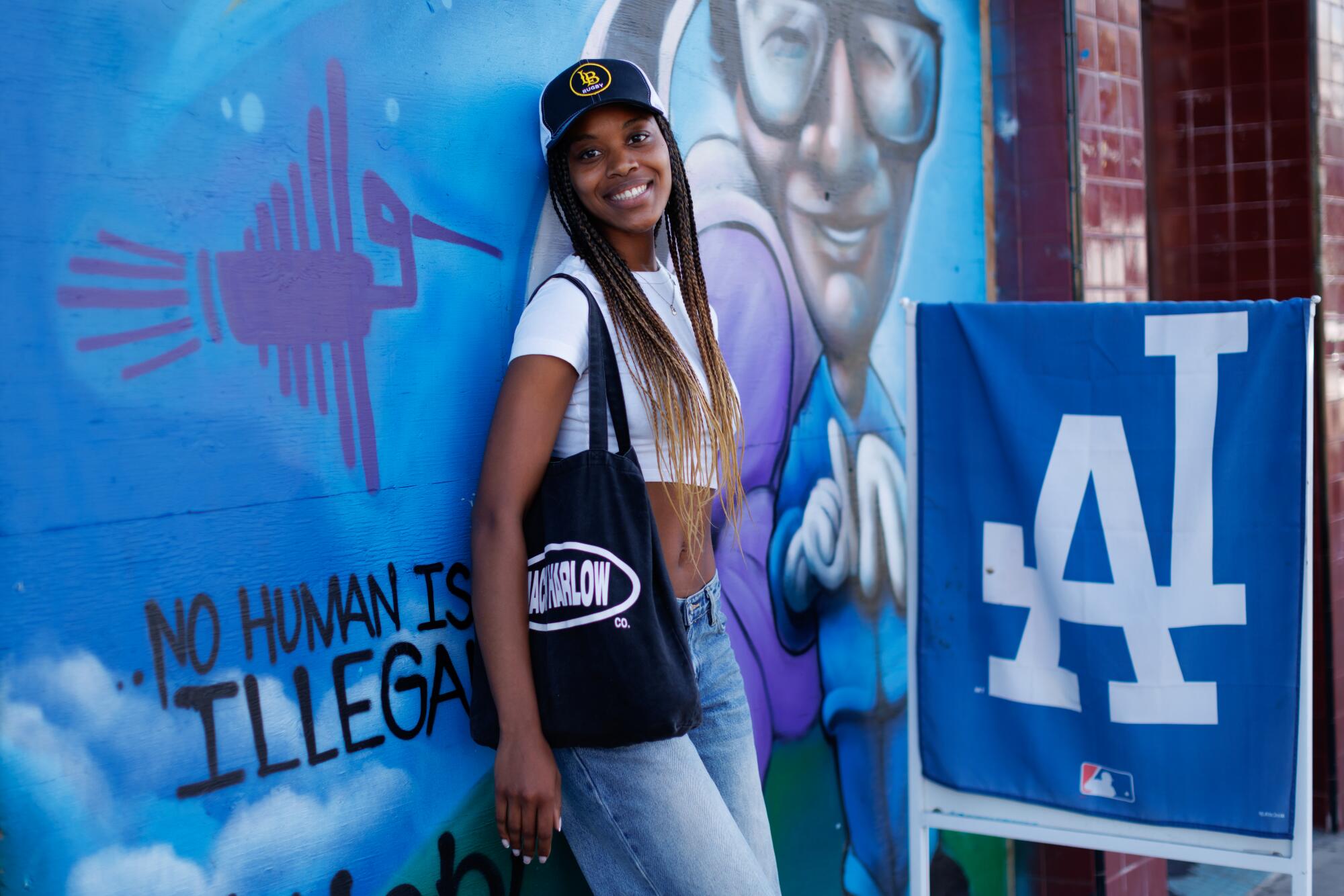 A person standing outside against a mural.