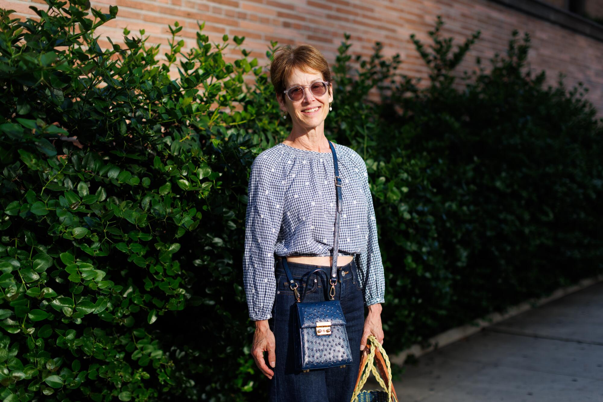 A person standing against a row of bushes.