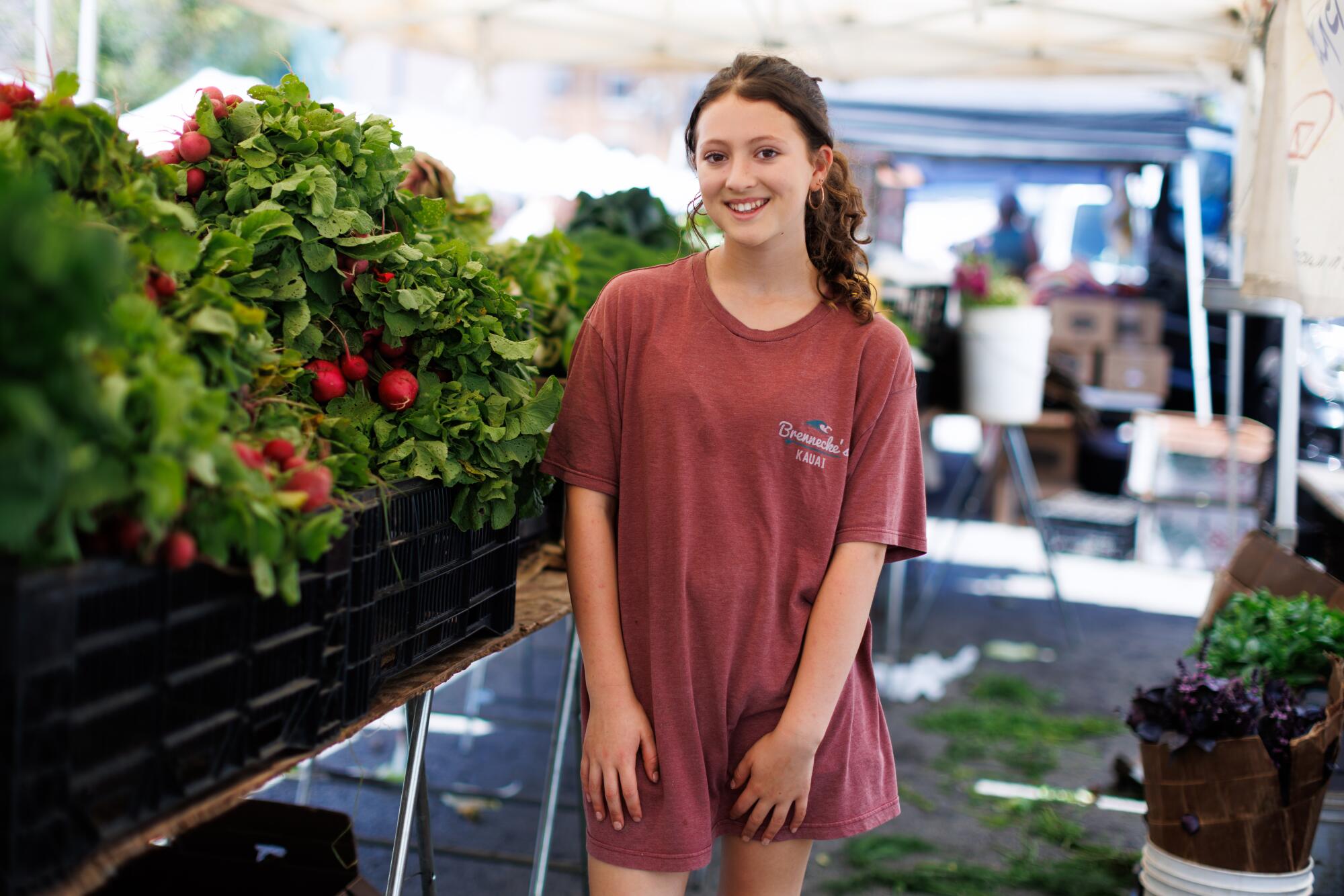 A young person standing at a farmers market.