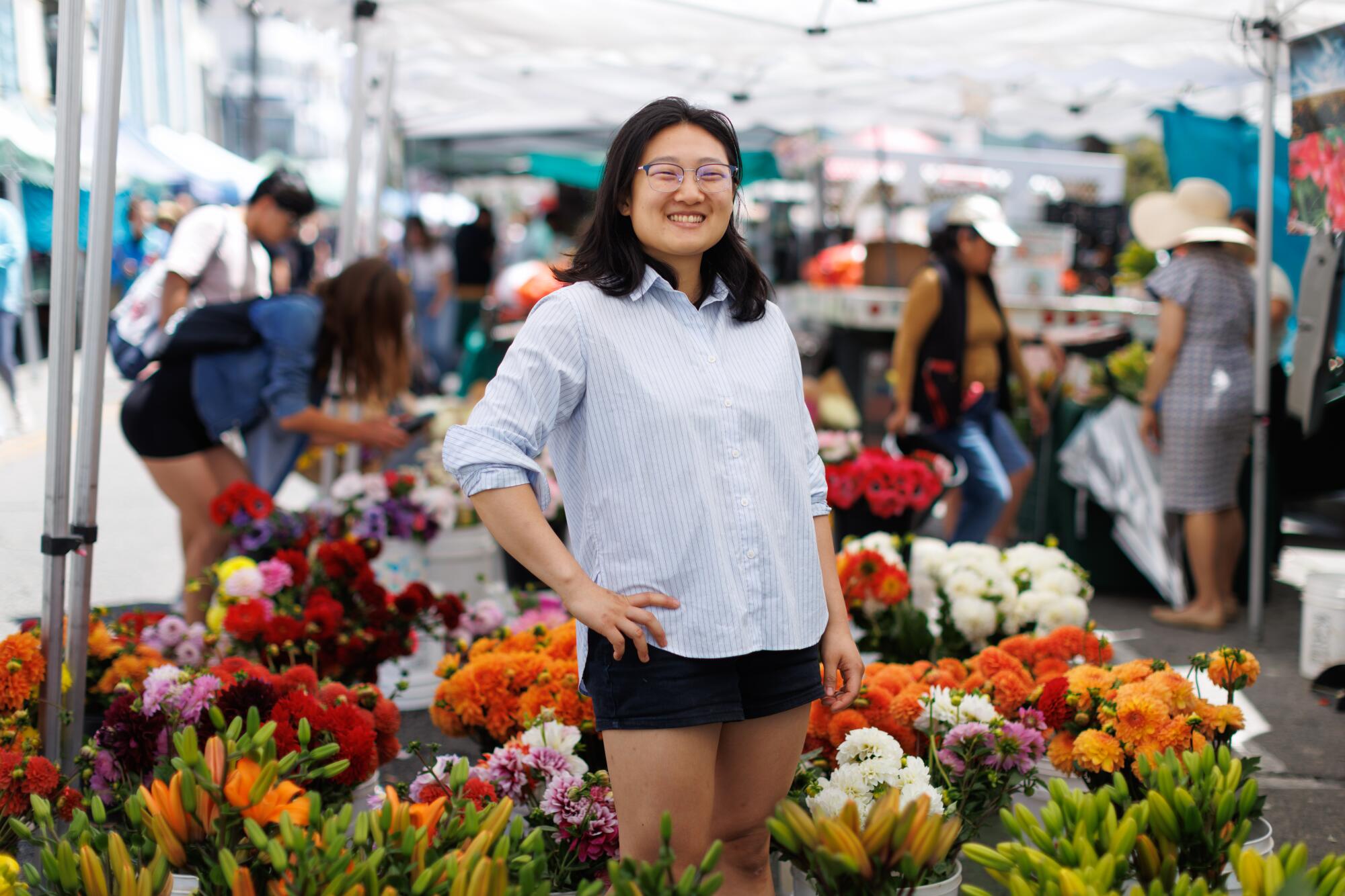 A person stands by a flower vendor at a farmers market.