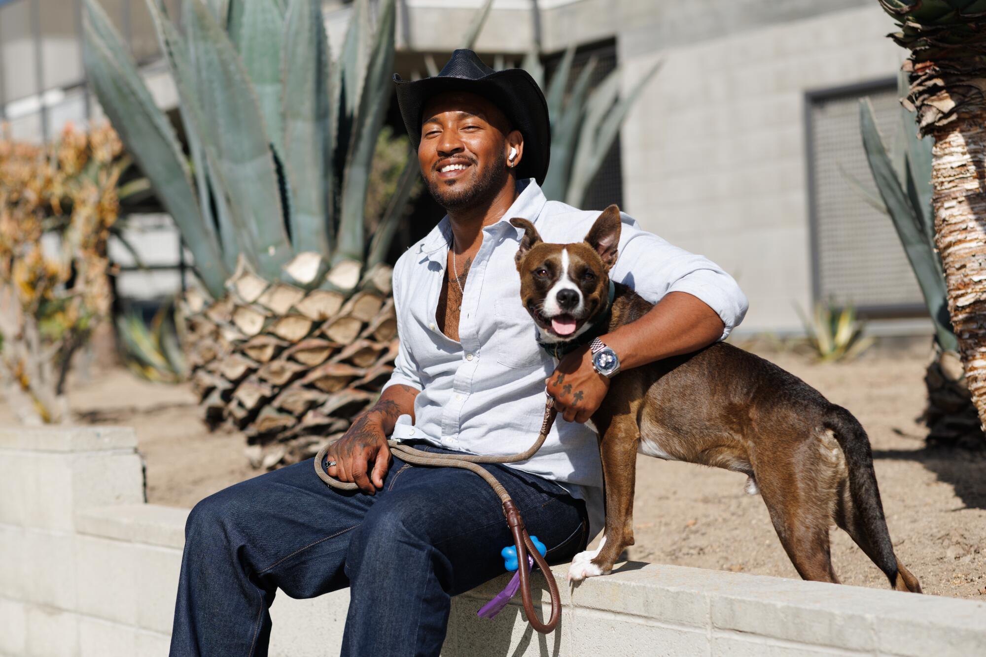 A person sits with his boxer mix at Venice Beach.