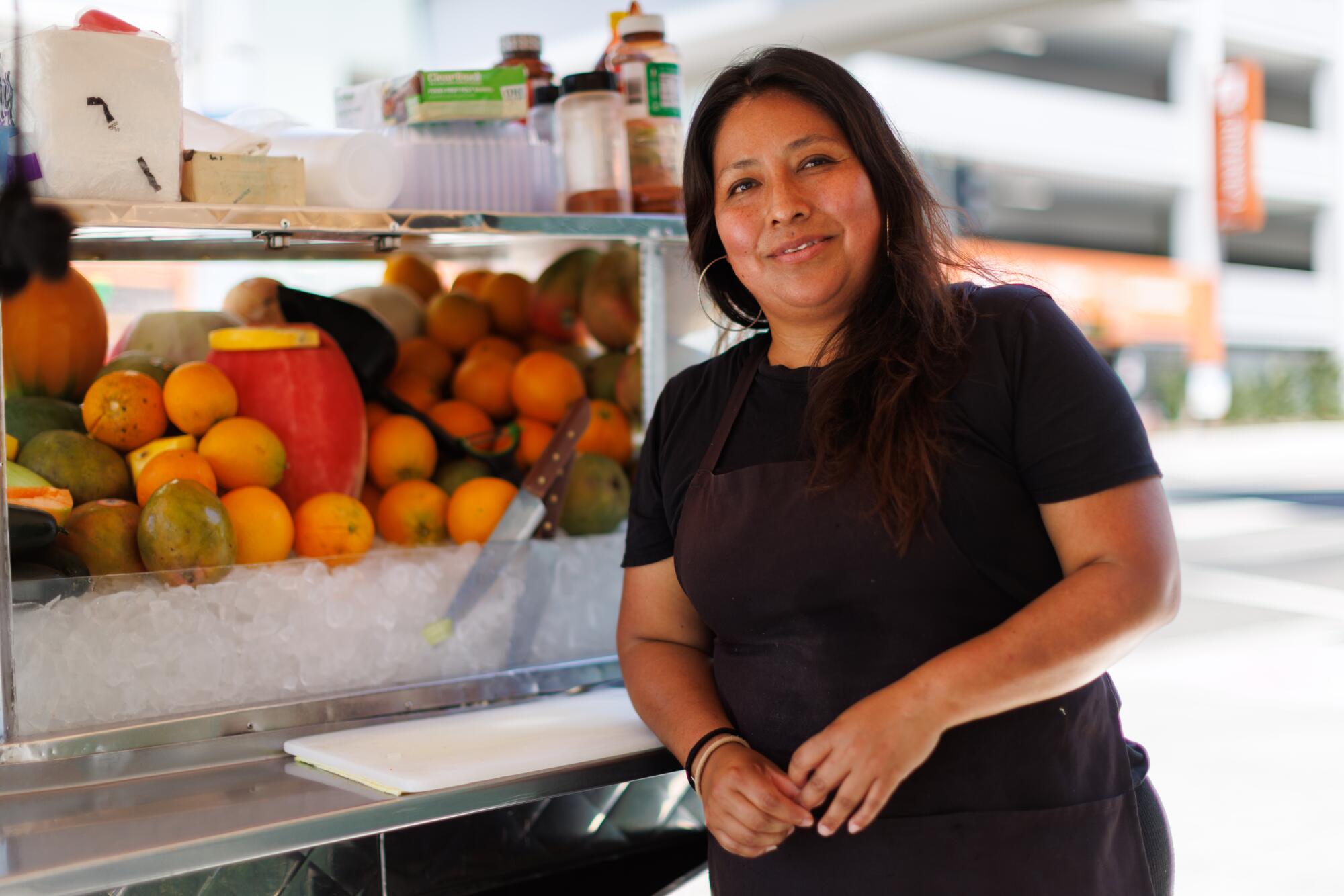 A person leaning against her fruit cart in Little Armenia.