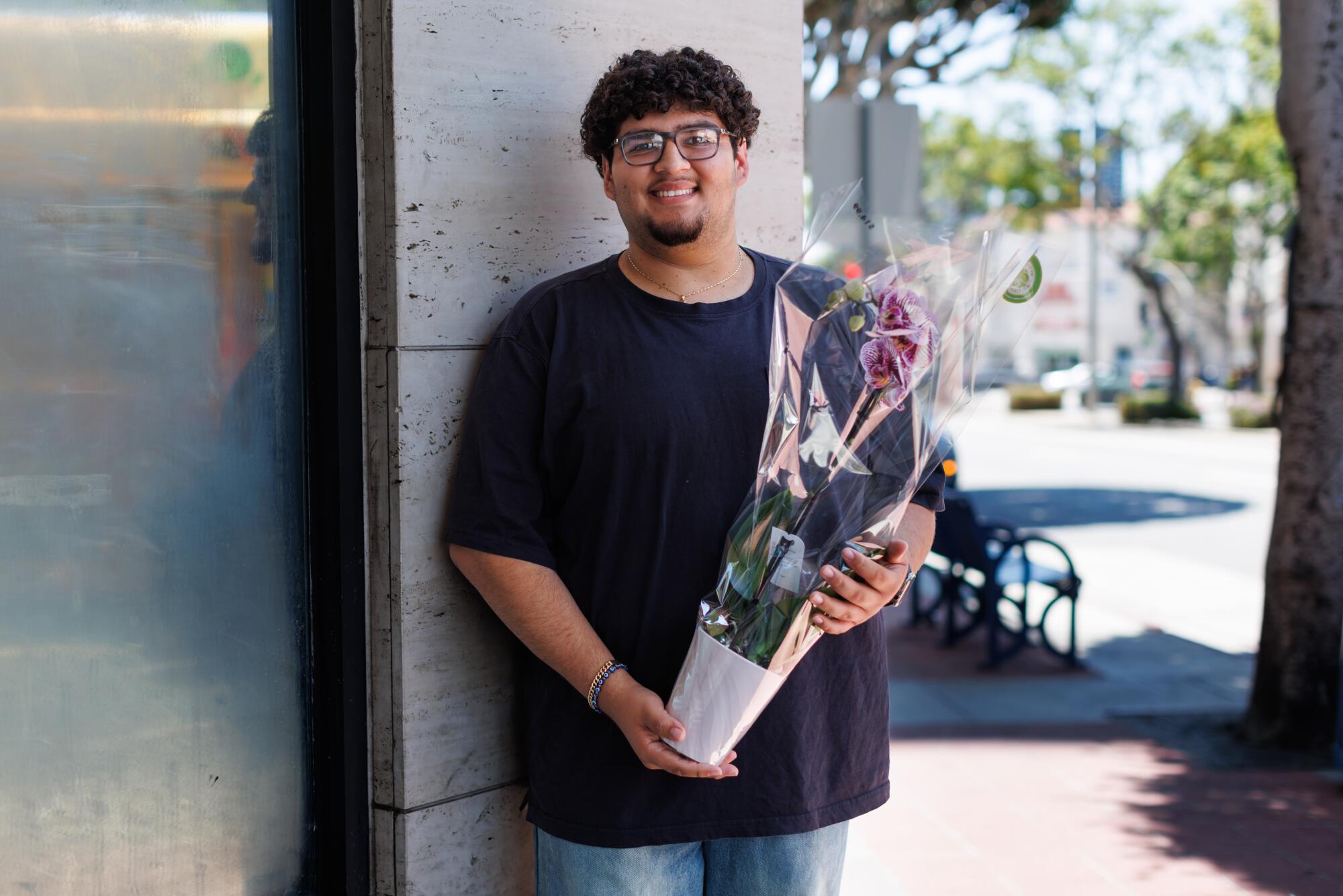 A person stands outside in Westwood holding a pot with a flower.