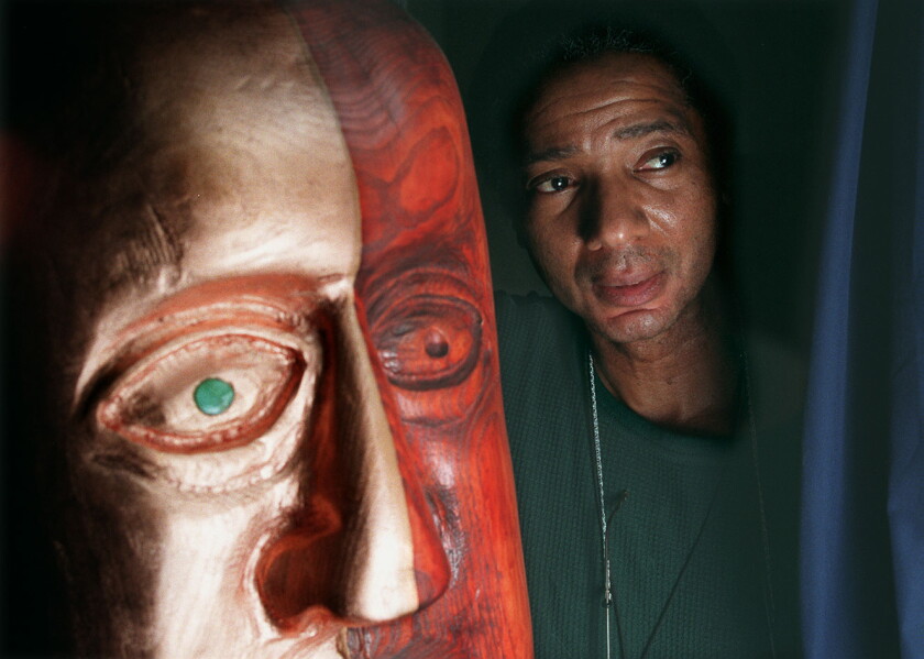 Milton Mizenburg, whose sculptures grace three vacant lots near his home at 41 place and Lake Park. This Mr. Mizenburg with his sculpture two face, carved from wood.